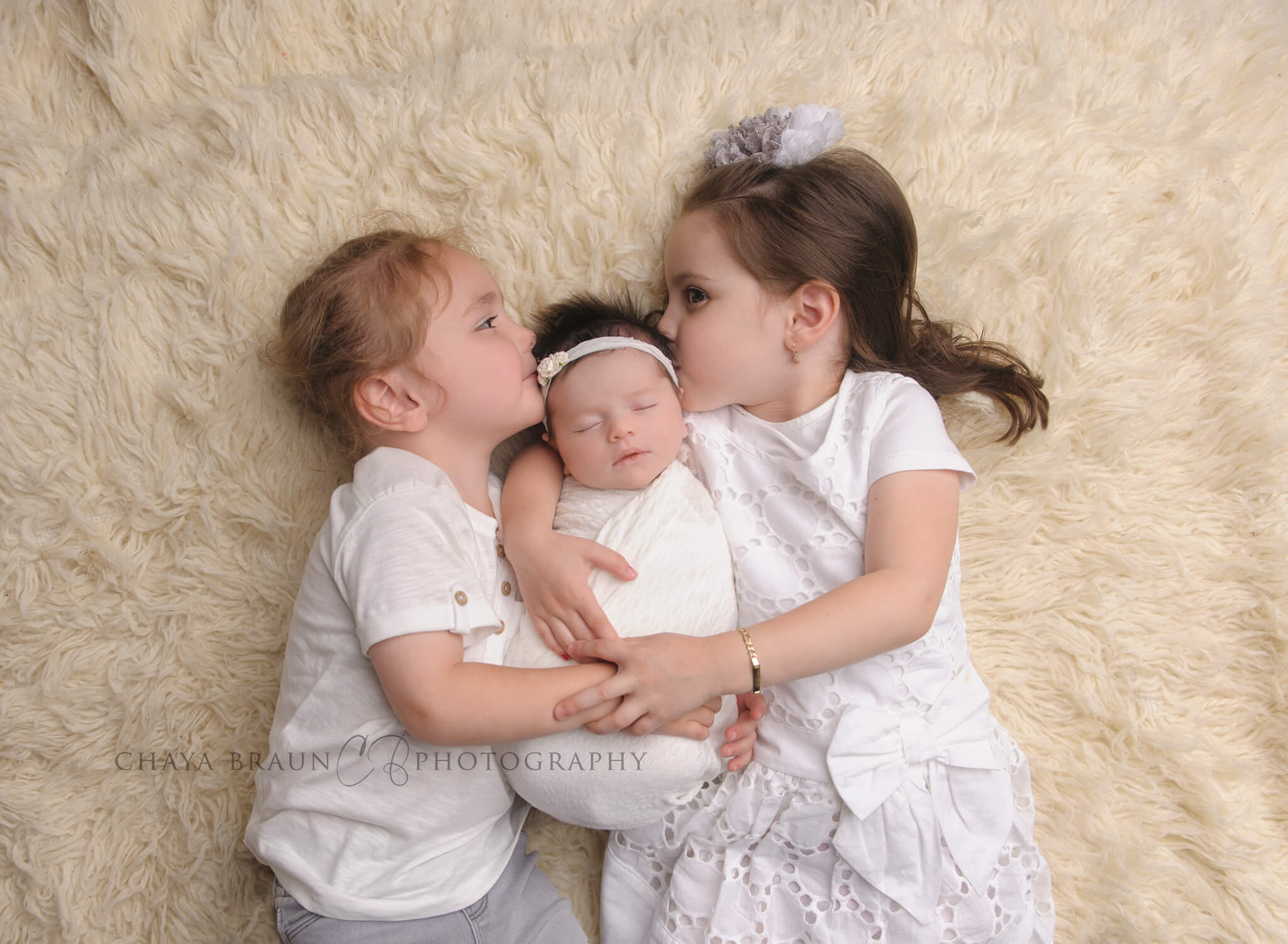 newborn and kissing siblings